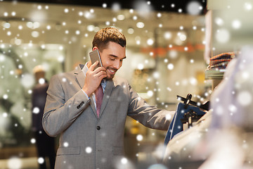 Image showing happy man calling on smartphone at clothing store