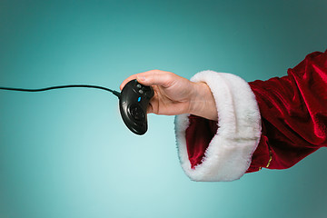 Image showing Hand of Santa Claus pressing on the remote gaming consoles