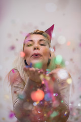 Image showing woman blowing confetti in the air