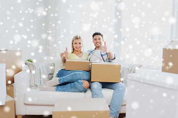 Image showing happy couple with boxes showing thumbs up at home