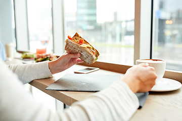 Image showing woman eating sandwich and drinking coffee at cafe