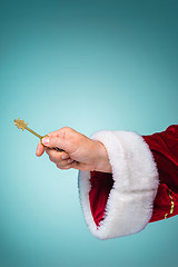 Image showing Hand of Santa Claus holding the key on blue background