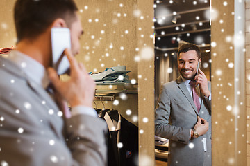 Image showing man calling on smartphone at clothing store mirror