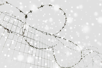 Image showing barb wire fence over gray sky and snow