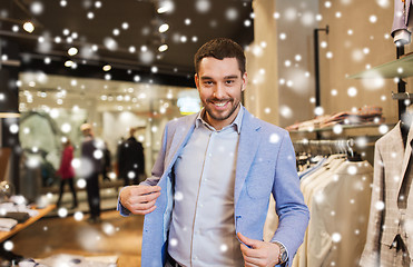 Image showing happy young man trying jacket on in clothing store