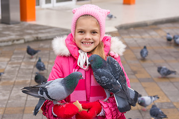 Image showing Pigeons sit on a girl that feeds them
