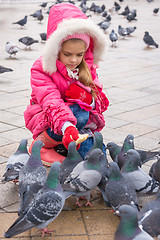 Image showing Seven-year girl feeding pigeons with bread in the street