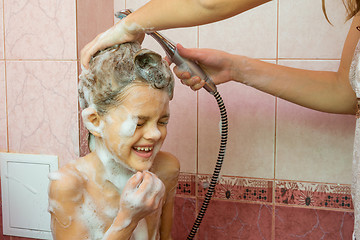 Image showing Mom washes the soap and shampoo in the shower with a seven-year daughter