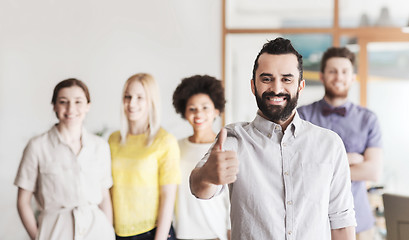 Image showing happy man showing thumbs up over team in office