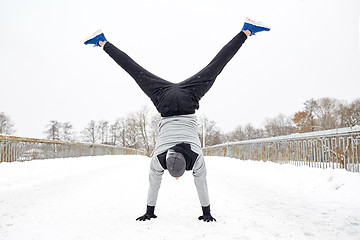 Image showing young man doing handstand in winter