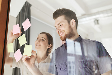 Image showing happy creative team writing on stickers at office