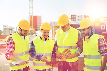 Image showing group of smiling builders with tablet pc outdoors