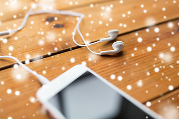 Image showing close up of smartphone and earphones on wood