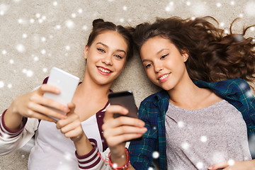 Image showing happy teenage girls lying on floor with smartphone