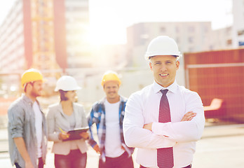 Image showing group of smiling builders in hardhats outdoors