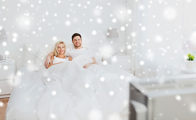 Image showing happy couple lying in bed at home and watching tv