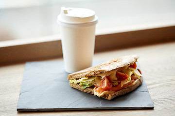 Image showing salmon panini sandwich and cup of drink at cafe