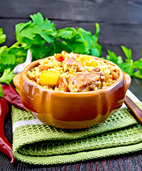 Image showing Rice with chicken and zucchini in clay bowl on board