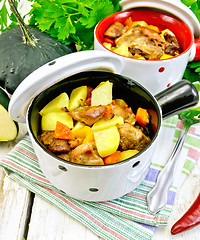 Image showing Roast meat and vegetables in white pots on napkin