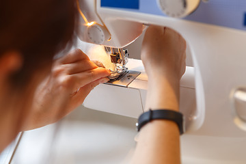 Image showing Girl sews fabric on machine