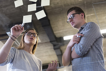 Image showing young couple at modern office interior writing notes on stickers