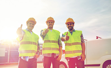 Image showing happy male builders in high visible vests outdoors