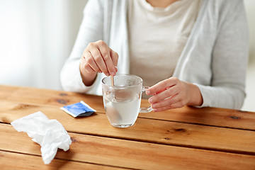 Image showing woman stirring medication in cup with spoon