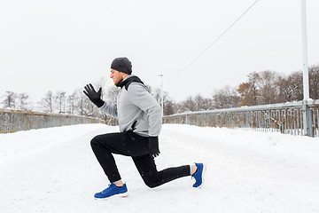 Image showing man exercising and doing squats on winter bridge