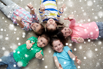 Image showing happy kids lying on floor and showing thumbs up