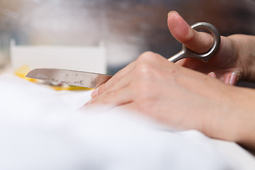 Image showing Girl with scissors cuts fabric