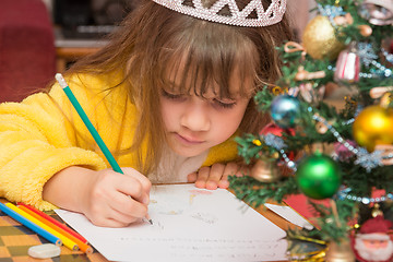 Image showing The girl draws a picture in a letter to Santa Claus