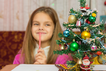 Image showing Girl happily thinking about a gift for the new year, focusing on a fur-tree