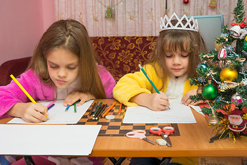 Image showing Two girls writing Christmas greeting letter sitting at the table at home