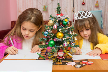 Image showing Two girls write a letter to Santa Claus, the focus is on the fur-tree in the middle