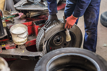 Image showing Professional auto mechanic replacing tire on wheel in car repair service.