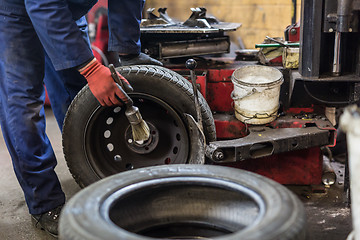 Image showing Professional auto mechanic replacing tire on wheel in car repair service.