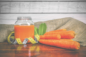 Image showing Jar with carrot juice on a wooden table