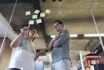 Image showing young couple at modern office interior writing notes on stickers