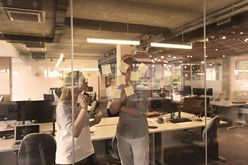 Image showing young couple at modern office interior writing notes on stickers