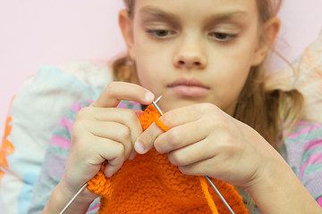 Image showing knits on the needles orange scarf, focusing on spokes