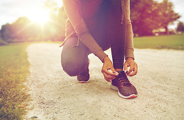 Image showing close up of woman tying shoelaces outdoors