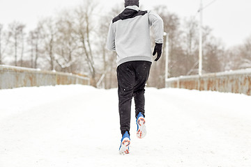Image showing man running along snow covered winter bridge road