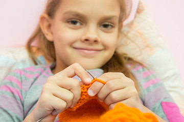 Image showing Happy girl knits on the needles, and looked into the frame, the camera focuses on the spokes