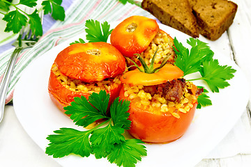 Image showing Tomatoes stuffed with bulgur and parsley in plate on light boar