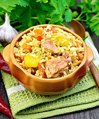 Image showing Rice with chicken and zucchini in clay bowl on dark board