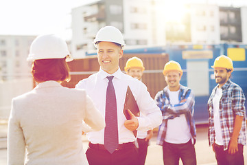 Image showing group of smiling builders in hardhats outdoors