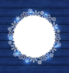 Image showing Christmas round frame made in snowflakes on blue wooden backgrou