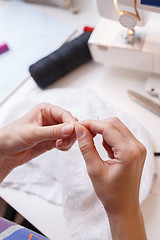 Image showing Dressmaker cuts thread in fabric