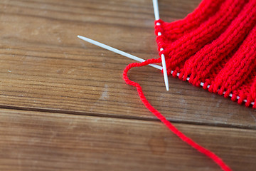 Image showing hand-knitted item with knitting needles on wood