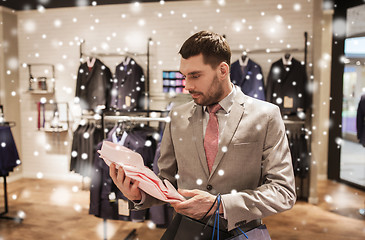 Image showing man with bags choosing shirt in clothing store